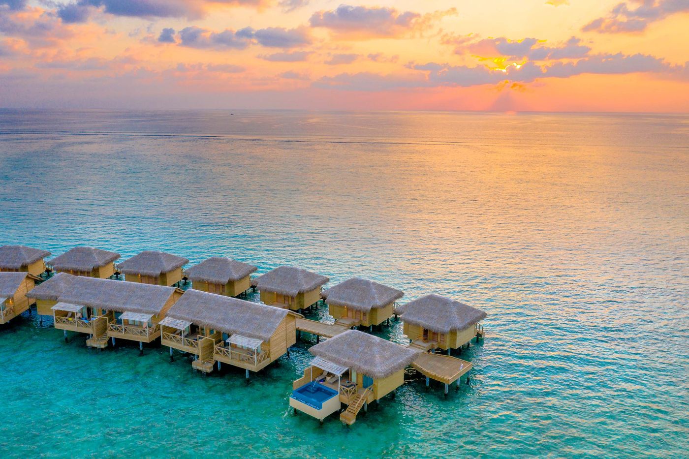 Aerial view of overwater villas at sunset